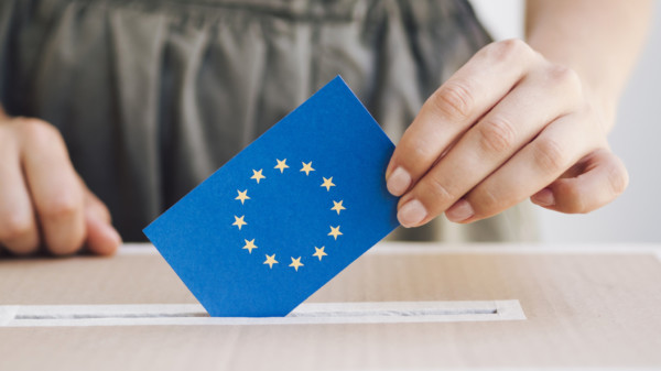 Eine Frau steckt eine Karte mit EU-Logo in eine Wahlurne